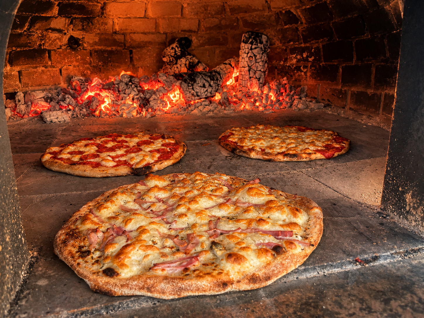 Pizzas horneándose en el horno de piedra de leña de Pool Bar